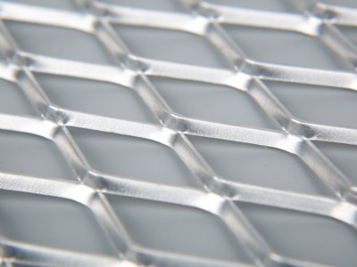A piece of stainless steel raised expanded metal sheet on the blue background.